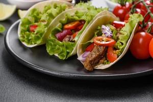 Mexican tacos with beef, tomatoes, avocado, onion and salsa sauce