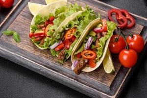 Mexican tacos with beef, tomatoes, avocado, onion and salsa sauce photo