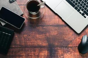 A laptop, phone, and other items on a wooden desk photo