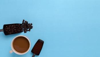 Coffee mug, coffee beans, ground coffee on a blue background photo