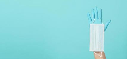 Hand wear surgical glove and holding face mask on mint background. photo
