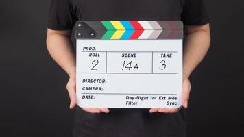 A man is hold Clapperboard with write in number on black background. photo