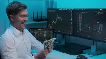 Joyful broker counts money on the background of charts