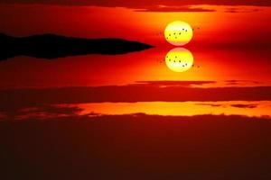 reflejo de la puesta de sol de nuevo la luz de la tarde nube en el cielo y pájaros volando foto