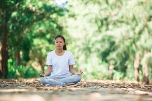 joven asiática haciendo yoga por la mañana en el parque. foto