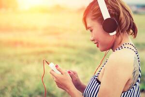 hermosa mujer con música de pie escuchando en los campos de flores. foto