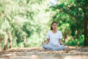 Young asian woman doing yoga in the morning at the park. photo