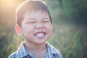 Cerca de lindo chico asiático jugando y sonriendo al aire libre.