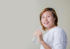 Young healthy woman holding bottle of water and smiles at camera photo