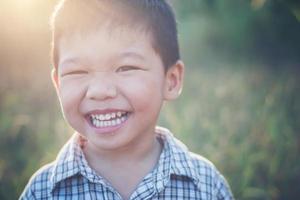 Cerca de lindo chico asiático jugando y sonriendo al aire libre.