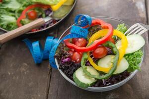 Fresh vegetables salad on  bowl with measuring  wooden background. photo