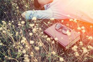 young woman napping on the dandelion field after reading book. photo