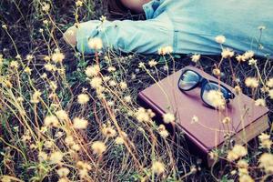 Vintage style of retro camera with book and glasses in the flowe photo