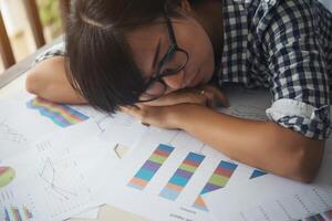 Mujer de negocios cansada dormida en una computadora portátil mientras trabajaba en su lugar de trabajo foto