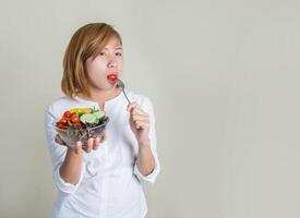 joven y bella mujer con ensalada de verduras y tenedor en la mano. foto