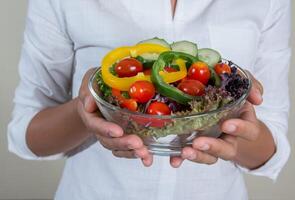 Bella mujer sosteniendo un plato de ensalada de verduras frescas foto