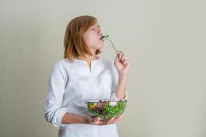 Young beautiful woman with vegetable salad bowl and fork in hand. photo