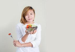 joven y bella mujer con ensalada de verduras y tenedor en la mano. foto