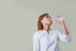 Young healthy woman holding bottle of water and smiles at camera photo