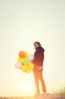 hipster woman holding balloons wearing black coat in the winter photo