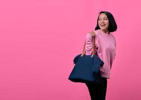 Portrait of happy young Asian woman holding bag while shopping photo