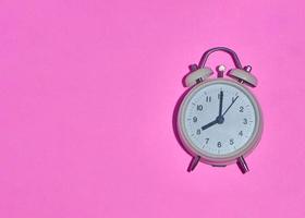 vintage alarm clock on light pink background photo