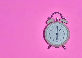 vintage alarm clock on light pink background photo