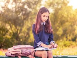Schoolgirl sit bench. Studying in school yard. Smart schoolgirl. photo