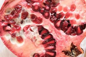 half of juicy pomegranate with pale red and white seeds photo