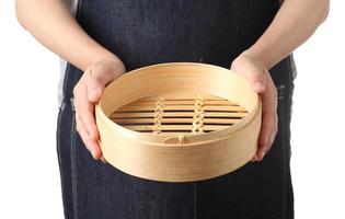 Chef holding empty chinese bamboo dumpling basket on white background photo