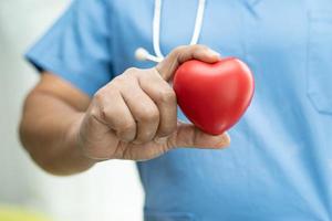 Asian senior woman patient holding red heart photo