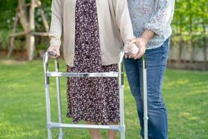 Ayudar y cuidar a la mujer mayor asiática usar andador en el parque foto