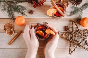 Woman holds cup of hot mulled wine in her hands