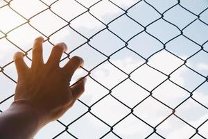 Hope concept,unhappy man hand sad hopeless at fence prison in jail, photo