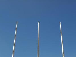 Flagpoles over blue sky photo