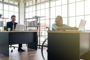 Mujer discapacitada asiática hablando con colegas en la oficina foto