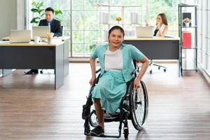 Mujer discapacitada asiática sentada en sillas de ruedas y trabajando en la oficina foto