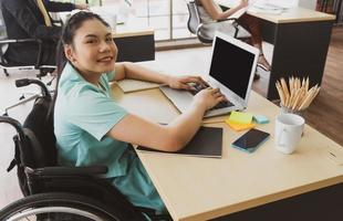 Mujer discapacitada sentada en silla de ruedas trabajando en la oficina