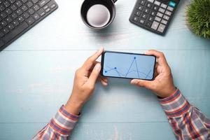 young man analyzing stock chart on smart phone photo