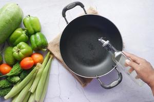 Pouring vegetable oil into frying pan. top view photo