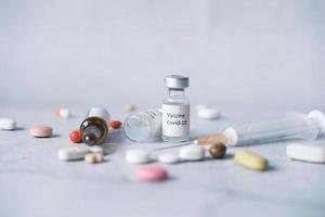 Close up of coronavirus vaccine, medical pills and syringe on white photo