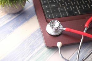 Medical Stethoscope on laptop on wooden table photo