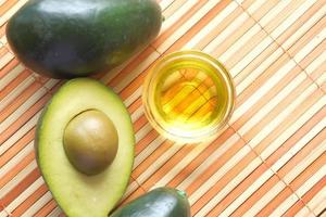 Top view of oil and slice of avocado on wooden table photo