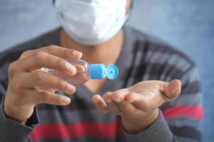 man in face mask using sanitizer liquid for preventing corona virus photo