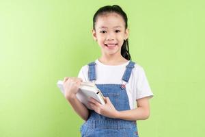 Portrait of Asian child holding book on green background photo