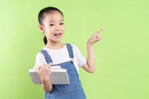 Portrait of Asian child holding book on green background photo