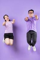 Young Asian couple jumping on purple background photo