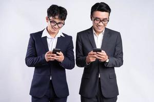 Two Asian businessmen using smartphone on white background photo