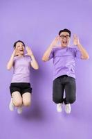 joven pareja asiática saltando sobre fondo púrpura foto