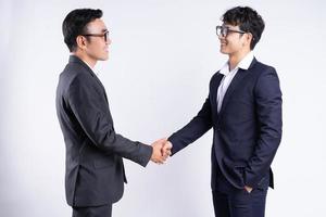 Two Asian business men shaking hands on a white background photo